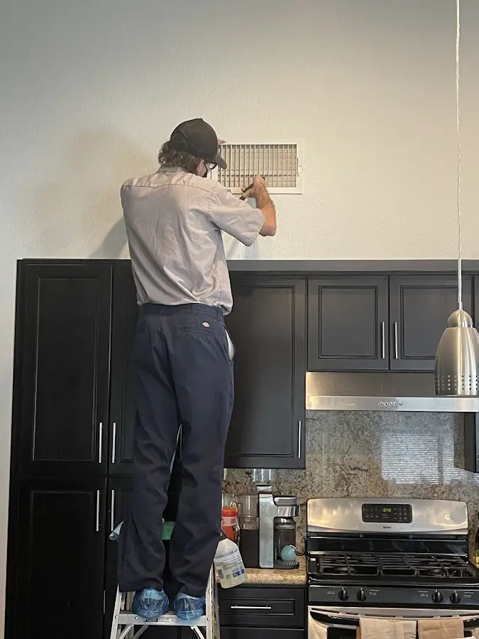 Technician inspecting an air vent during HVAC service in Apopka